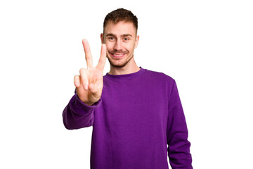 Young caucasian man cut out isolated joyful and carefree showing a peace symbol with fingers.