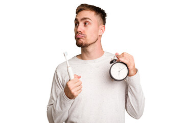 Young man holding an electric brush and an alarm clock cut out isolated