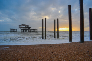 Fototapeta premium Burnt out Brighton Pier during a storm and sunset