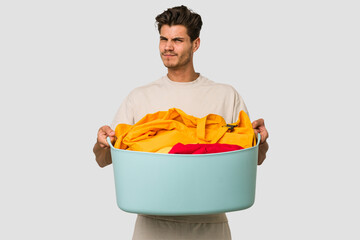 Young caucasian man doing laundry isolated on white background