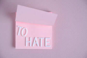 Word hate laid out white letters pink piece paper.Concept hatred, anger and denial.