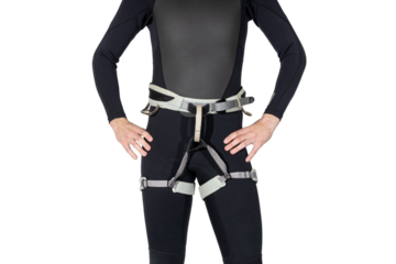 Man wearing a black wetsuit and gray climbing harness for canyoneering on a white isolated background with hands on hips. 