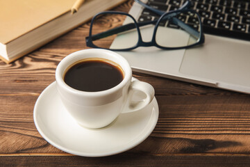 Laptop with coffee cup, eyeglasses, notepad and pen on texture background, office concept. Business concept. Work at home. Workspace with laptop. Mocap. Place for text. Copy space.