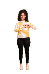 Young african american woman with curly hair cut out isolated smiling and showing a heart shape with hands.
