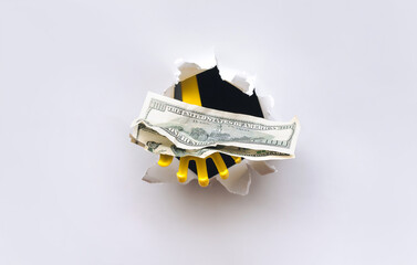 Stolen money. A yellow plastic toy hand reaches for the hundred-dollar through a torn hole in white...