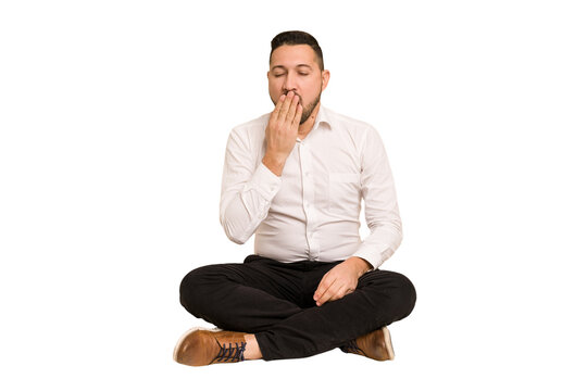 Adult latin man sitting on the floor cut out isolated yawning showing a tired gesture covering mouth with hand.