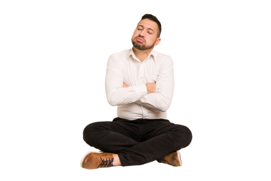 Adult latin man sitting on the floor cut out isolated tired of a repetitive task.