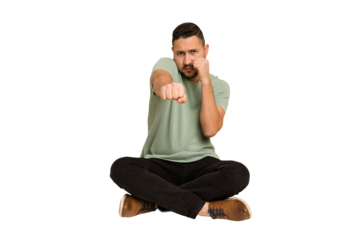 Adult latin man sitting on the floor cut out isolated throwing a punch, anger, fighting due to an argument, boxing.