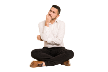 Adult latin man sitting on the floor cut out isolated thinking and looking up, being reflective, contemplating, having a fantasy.