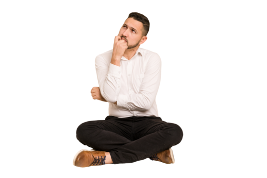 Adult latin man sitting on the floor cut out isolated thinking and looking up, being reflective, contemplating, having a fantasy.