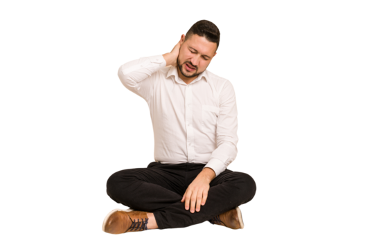 Adult latin man sitting on the floor cut out isolated having a neck pain due to stress, massaging and touching it with hand.