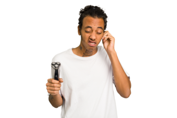 Young African American man holding a razor isolated covering ears with hands.