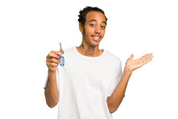 Young African American man holding home keys isolated showing a copy space on a palm and holding another hand on waist.