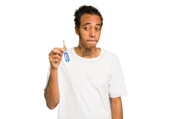 Young African American man holding home keys isolated confused, feels doubtful and unsure.