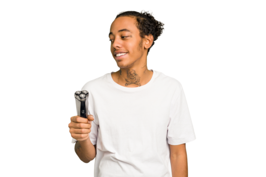 Young African American man holding a razor isolated looks aside smiling, cheerful and pleasant. - Powered by Adobe