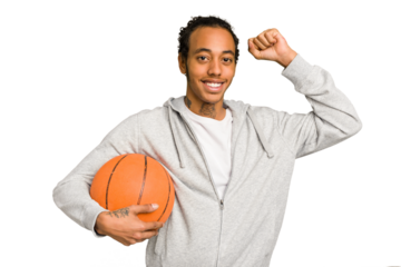Young african american man playing basketball isolated raising fist after a victory, winner concept.