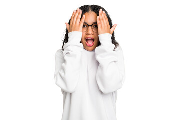 Young african american woman with curly hair cut out isolated having fun covering half of face with palm.