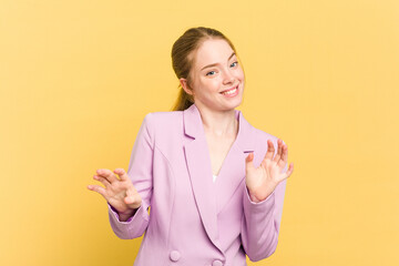 Young caucasian redhead woman isolated on yellow background rejecting someone showing a gesture of...