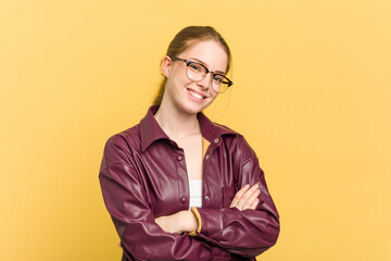 Young caucasian redhead woman isolated on yellow background who feels confident, crossing arms with determination.