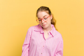Young caucasian redhead woman isolated on yellow background shrugs shoulders and open eyes confused.