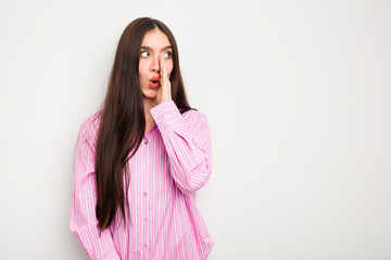 Young caucasian woman isolated on white background is saying a secret hot braking news and looking aside