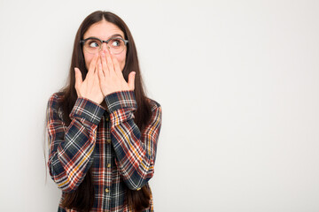 Young caucasian woman isolated on white background thoughtful looking to a copy space covering mouth with hand.