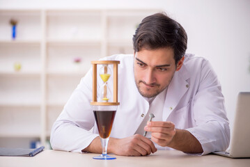 Young male chemist examining soft drink