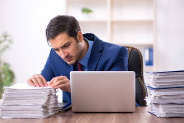 Young male employee and too much work in the office