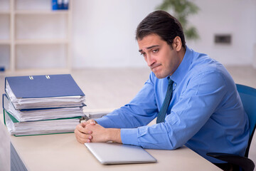 Young male employee and too much work in the office