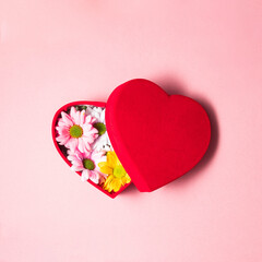 Flowers in heart shaped box on pastel light pink background. Modern Valentine's Day concept. Creative love idea. Minimalistic Mother's Day composition.