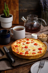 Creamy shortbread pie. Quiche with cherry tomatoes and chicken in the village on a wooden table.