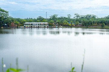 A building near a river taken from a far with a lot of trees around it