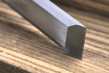 Steel silver carpenter's chisels on brown wood grain background.