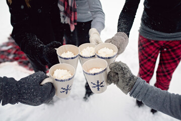 Cropped hands of family toasting drinks in mugs during winter