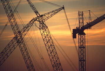 Silhouette of cranes at commercial building construction site at dusk, Dallas, TX.