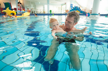 Father with baby in public swimming pool