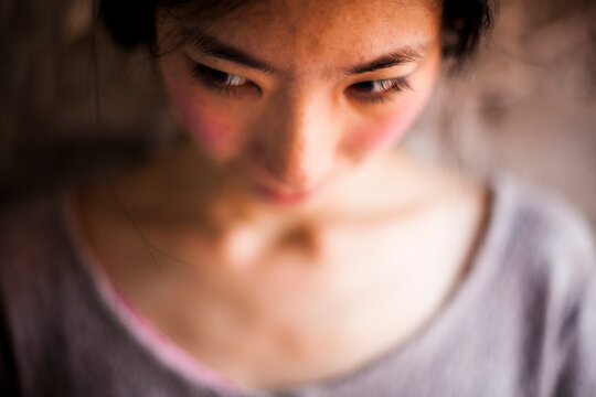 A Young Asian Woman Looking Down And Away.