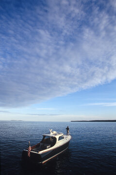 A man stands on the bow of a motor boat near Southwest Harbor, Maine.