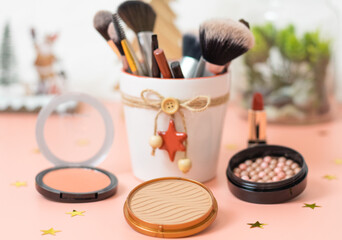 A set of cosmetics on a pink background with a christmas decoration.