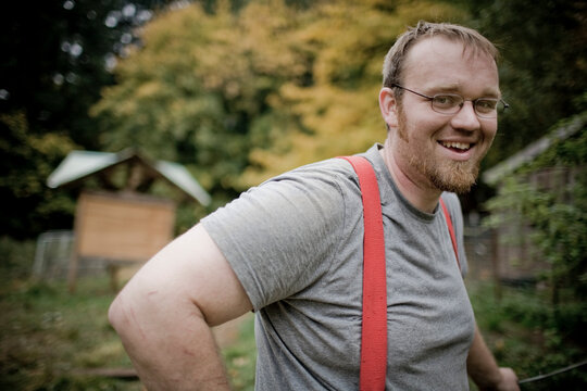 A young man wearing red suspenders on a farm.