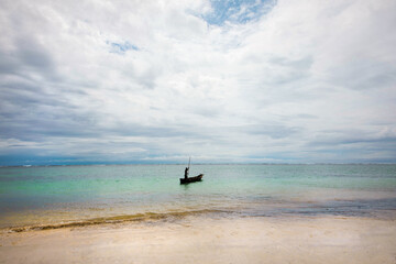 African fisher man stands beside his fishing boat