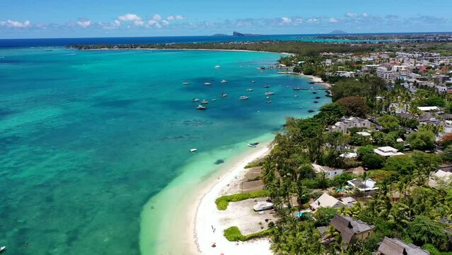 Mauritius - aerial video landscape view along the coastline at Troy aux Biches Beach and Mont Choisy Beach, with people walking on beach and boats swimming in the water of Indian Ocean, video footage 