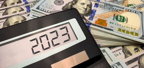 Energy and financial crisis in the world in 2023. The ever-increasing cost of energy, food and goods. Calculator and many banknotes of 100 US dollars