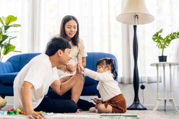 Portrait of enjoy happy love asian family father and mother  giving hi five with cute little asian girl child smiling play and having fun moments good time in at home