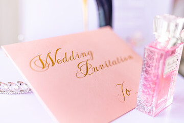 Wedding invitation on pink paper golden letters close up
