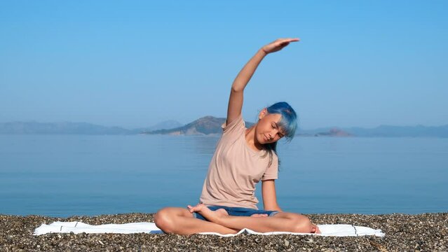 Yoga twists for spinal cord. A young nice girl twist her spinal cord and hands practicing yoga on the sunny beach.
