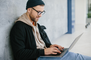 young software developer man using laptop computer writing programming code while sitting on the...