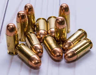 Twelve full metal jacket 45acp caliber bullets together on a white wooden background
