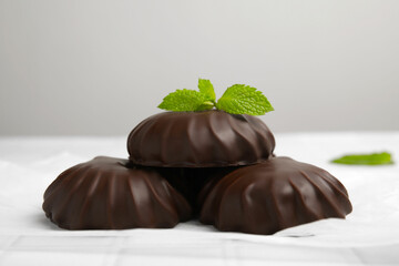 Delicious chocolate covered zephyrs with mint on white table