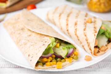 Delicious hummus wraps with vegetables on table, closeup